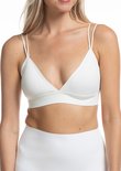 Vrouw met blonde haren in witte bralette, witte top.