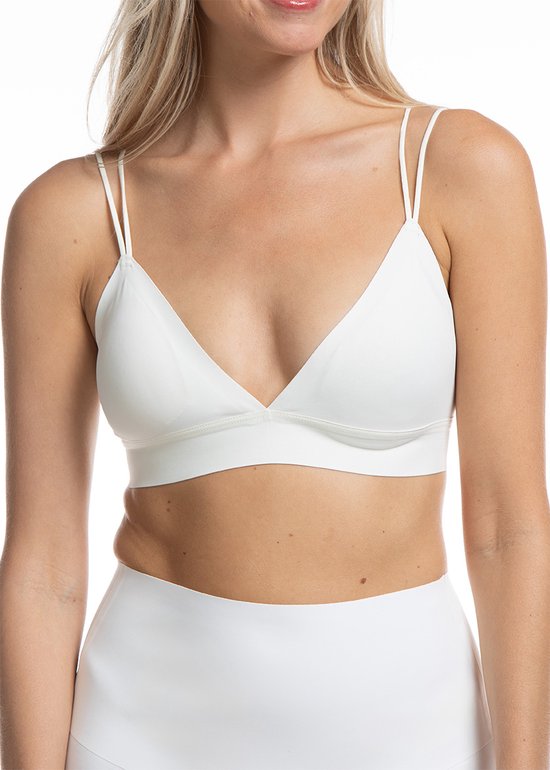 Vrouw met blonde haren in witte bralette, witte top.