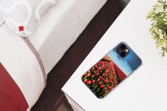 iPhone 13 hoesje met een veld met roze en rode tulpen, op een nachtkastje naast een bed.