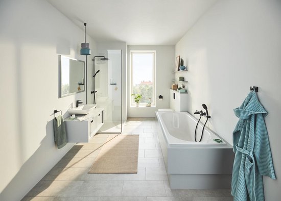 Stijlvolle badkamer met bad, douche, wastafel en een matzwarte toiletrolhouder bij de toiletruimte.