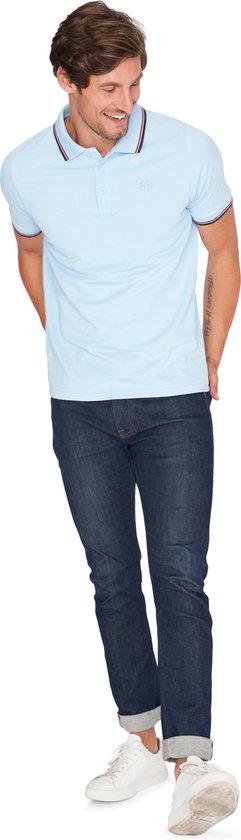 Man in lichtblauw poloshirt met marineblauwe en rode strepen op de kraag en mouwen, met jeans.