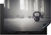 KitchenYeah® Inductie beschermer 77x51 cm - Verschillende kettlebellgewichten op de vloer in een fitnessruimte - Kookplaataccessoires - Afdekplaat voor kookplaat - Inductiebeschermer - Inductiemat - Inductieplaat mat