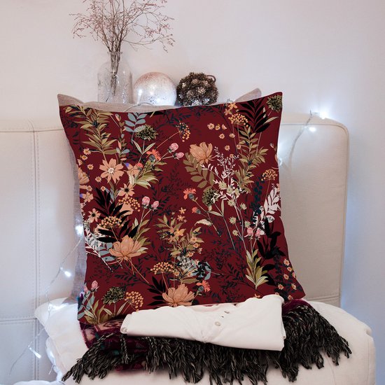 Kussenhoes met bordeauxrode achtergrond, veelkleurig bloemenpatroon, op een bankje met decoratie.