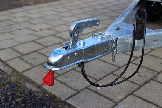 Aanhangerkoppeling met beveiligingsketting, rode punt en zilverkleurige hendel.
