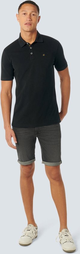 Model draagt een zwart poloshirt en een grijze spijkerbroekshort.