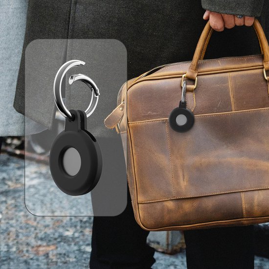 Een zwarte hoes voor een Apple AirTag met een zilveren sleutelring, bevestigd aan een leren tas.