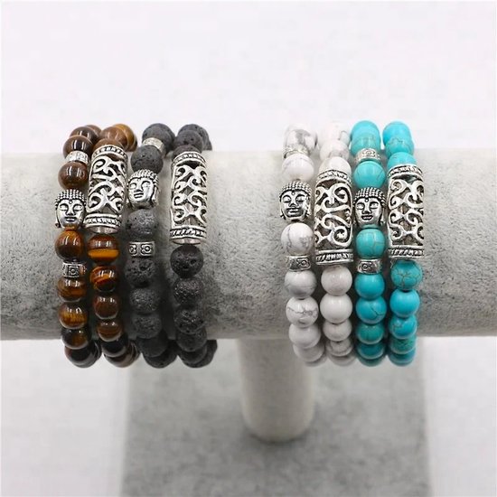 Vier armbanden op een grijze standaard: twee met bruine tijgeroog en zwarte lavakralen, en twee met witte en turquoise kralen. Elke armband heeft Buddha kop- en spiraalvormige spacers.
