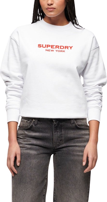 Sweat blanc Superdry New York sur un mannequin, avec inscription rouge sur la poitrine.