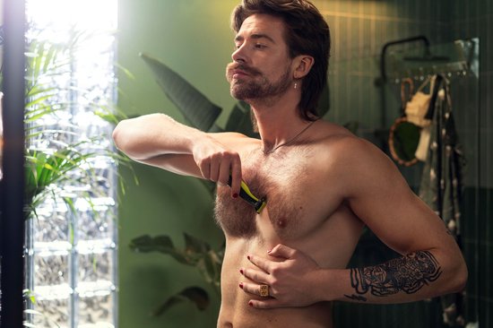 Man met snor en tatoeages scheert borstkas met Philips OneBlade.
