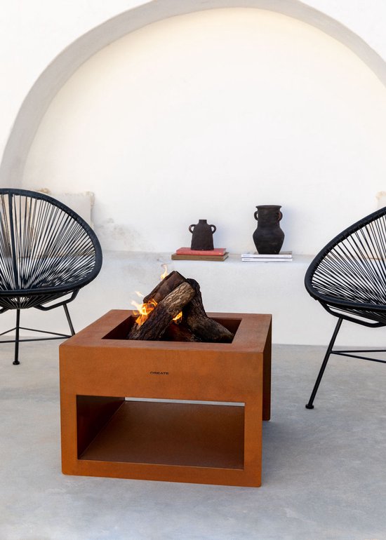 Vierkante cortenstaal tuinvuurplaats met brandend hout, op een terras tussen twee zwarte stoelen.