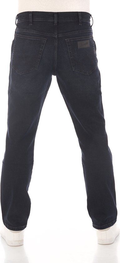 Achterkant man in donkerblauwe straight fit jeans en witte sneakers.