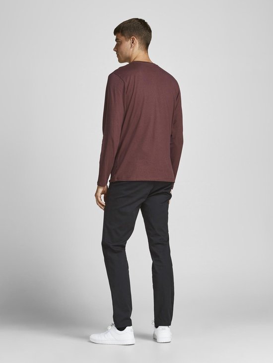 Man in bordeaux rode longsleeve en zwarte slim fit chino broek, gezien van de achterkant.