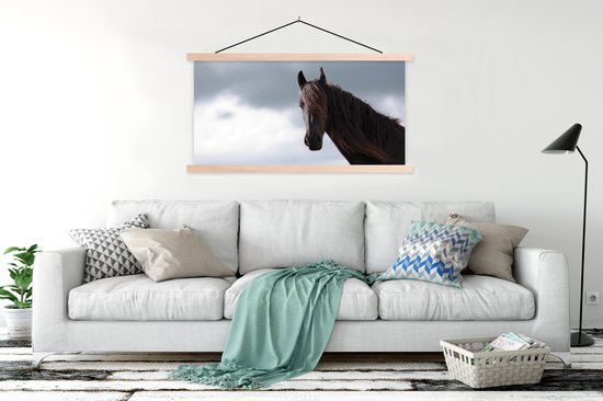 Wandposter met zwart paard in houten latten boven een witte bank met mintgroene plaid en decoratieve kussens.
