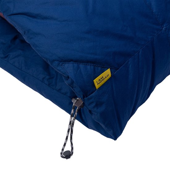 Detail van de donkerblauwe slaapzak met opgestikte gele 'I AM NOMAD' label en trekkoord.