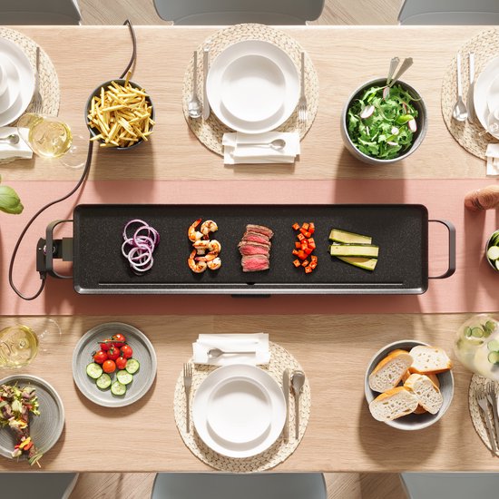 Appareil à raclette avec steak, crevettes, oignon, poivron et courgette, avec frites, salade et pain.
