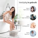 Vrouw bij bad, met voeten in voetenbad. Iconen met tekst "Werkt tegen ziekte", "Werkt tegen werkdruk", "Laat je ontspannen", "Werkt tegen kou".