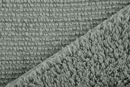 Close-up van de textuur van een zachtgroene badmat met een grof, pluizig weefsel en een gestreept patroon.