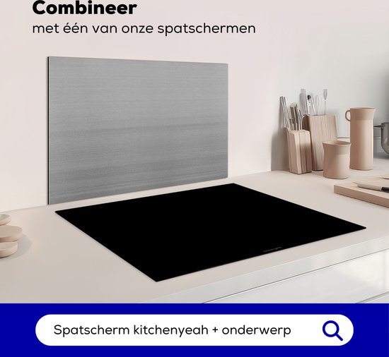 Zwarte inductiebeschermer naast een metalen spatscherm boven een kookplaat.