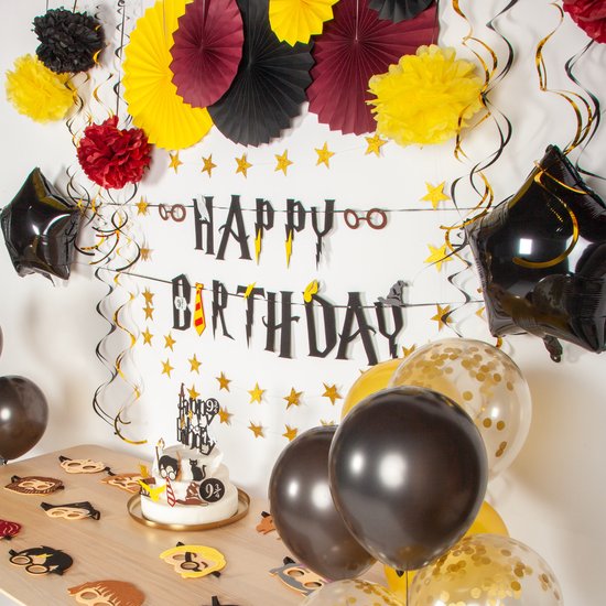 Een gedekte tafel voor een tovenaarsfeest met taart, ballonnen en decoraties.