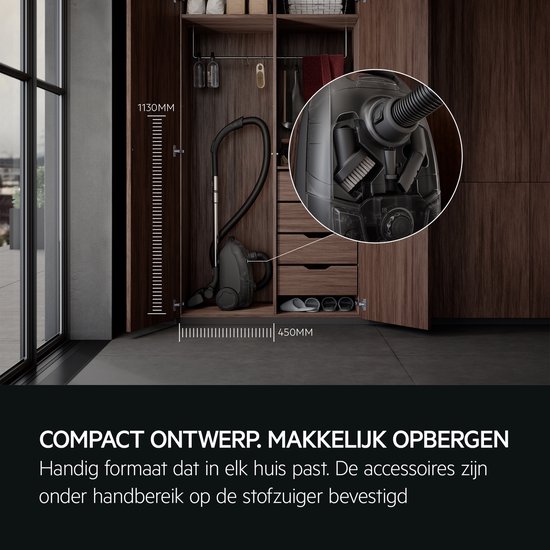 Grijze stofzuiger met slang opgeborgen in een open kast naast een raam, met een maataanduiding van 1130mm en 450mm.