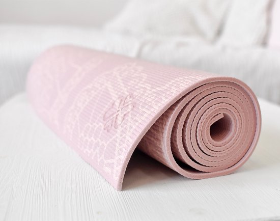 Een roze yogamat met een wit bloemenpatroon, gedeeltelijk opgerold.