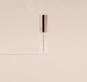 Transparante lipgloss tube met "hey honey!" erop en een gouden dop, op een egale achtergrond.