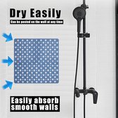 Tapis antidérapant carré bleu avec de nombreuses ouvertures rondes, suspendu à un mur de douche.