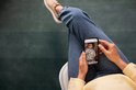 Persoon in spijkerbroek houdt smartphone vast met beeld babyfoon van slapende baby.