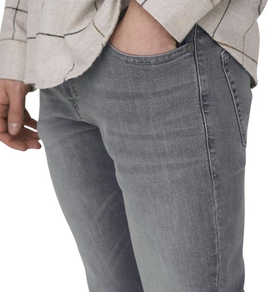 Close-up van de zijkant van een grijze jeans, met de hand in de zak.