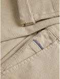 Detail van beige chino broek met omgeslagen broekspijp en een blauwe bies.