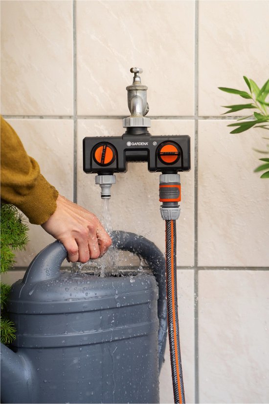 Vrouw vult een grijze gieter met water uit een GARDENA waterverdeler.