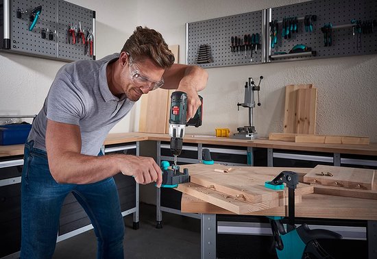Man met bril gebruikt Wolfcraft deuvelmal om gaten te boren in hout.
