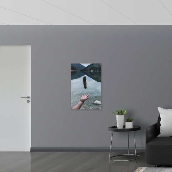 WallClassics - Toile - Plume flottant au-dessus de la main dans un paysage de montagne - 60x90 cm Photo sur toile (Décoration murale sur toile)