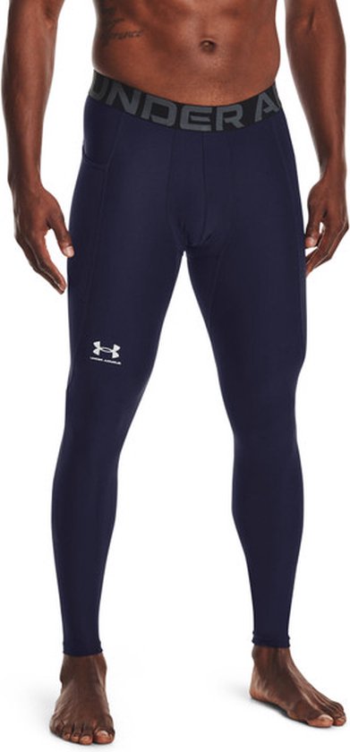 Model draagt een donkerblauwe sportlegging met een wit Under Armour-logo en merk-tailleband.