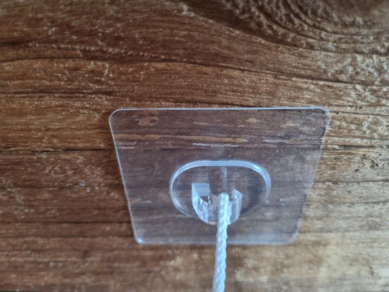Transparante plakhaak met wit touwtje op een houten achtergrond.