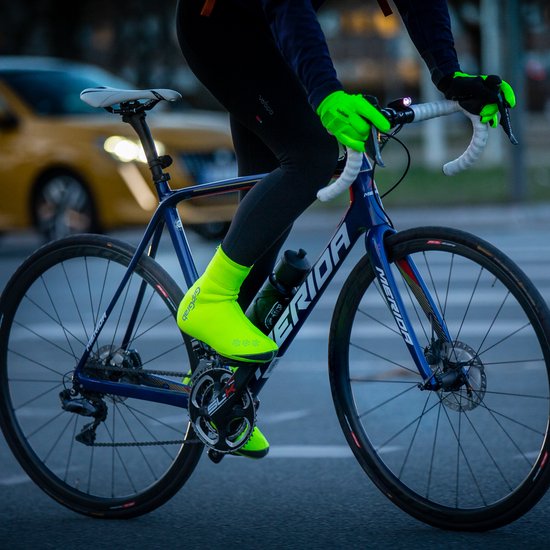 Fietser met een blauw Merida racefiets, neongele overschoenen en handschoenen.