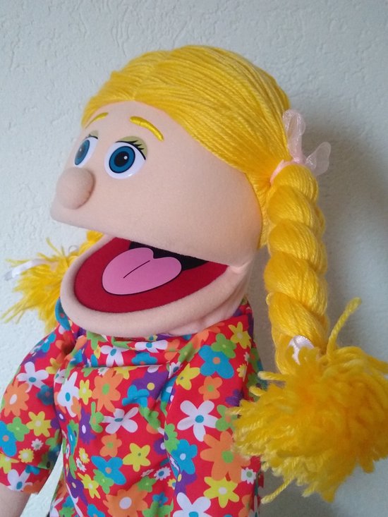 Close-up van buiksprekpop Cindy's gezicht met haar bloemenblouse en blonde vlechten.