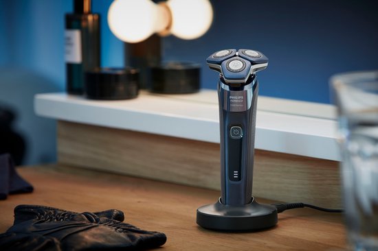 Rasoir Philips Norelco Série 7000 sur un socle, près d'un miroir et d'articles de toilette.