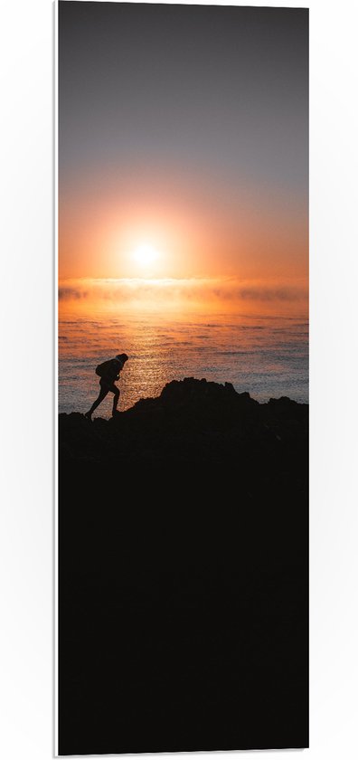 WallClassics - PVC Schuimplaat- Man lopend over Berg aan de Zee met Zonsondergang - 30x90 cm Foto op PVC Schuimplaat