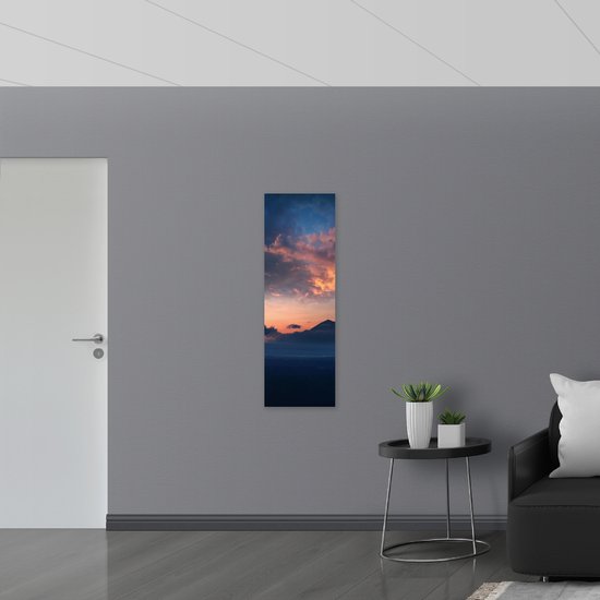 WallClassics - Muursticker - Bergen in het Landschap onder Oranje Lucht - 40x120 cm Foto op Muursticker