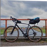 WallClassics - Dibond - Zwarte Wielrennersfiets voor rode Brug - 80x80 cm Foto op Aluminium (Wanddecoratie van metaal)