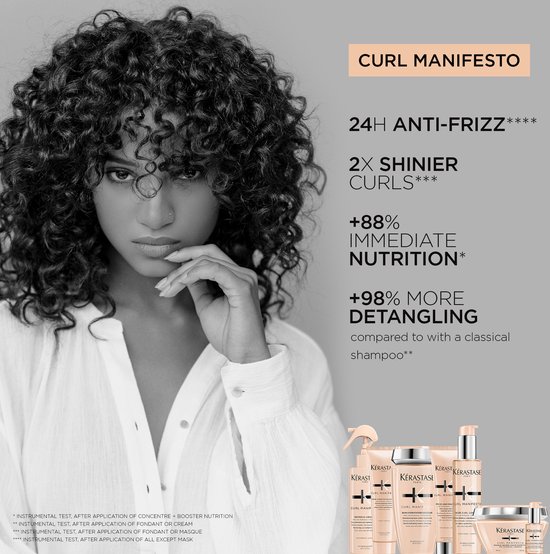 Portrait d'une femme aux cheveux bouclés magnifiquement définis, avec un présentoir de produits Kérastase en arrière-plan.