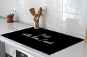 Zwarte kookplaatbeschermer met witte tekst "I kiss better than I cook", met houten keukengerei.