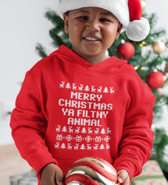 Jongen draagt rode kerst hoodie met witte tekst 'MERRY CHRISTMAS YA FILTHY ANIMAL' en kerstprintjes. Staat voor kerstboom.