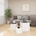Woonkamer met witte kubus bijzettafels, waar een plant, kussen, zandloper en boeken op staan.