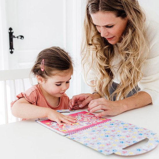 Une jeune fille et une femme regardent ensemble un livre de autocollants Mini MyMy avec des animaux mignons et des cœurs.