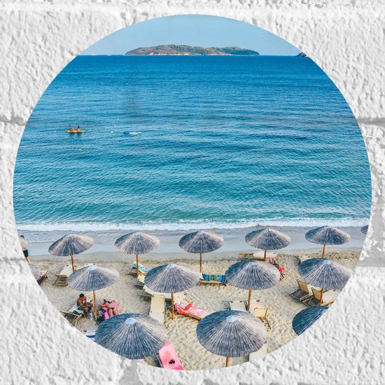 WallClassics - Muursticker Cirkel - Rieten Parasols met Ligbedjes op het Strand - 20x20 cm Foto op Muursticker