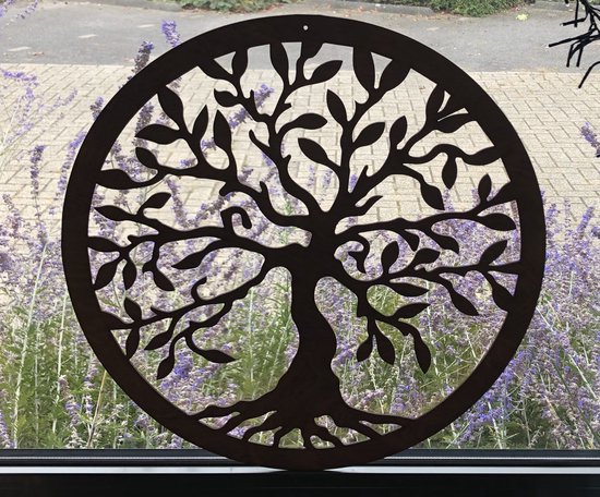 Décoration murale ronde en bois marron avec un motif d'arbre de vie, devant des fleurs violettes.