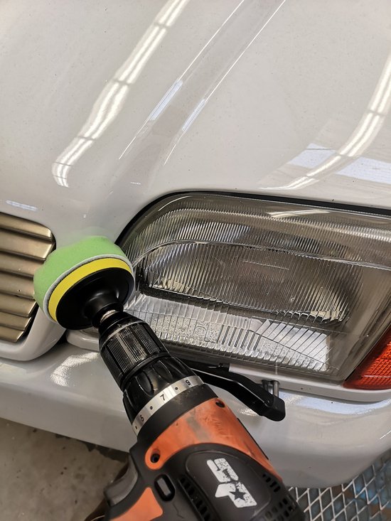 Boormachine met groen polijsthulpstuk in gebruik op een koplamp.