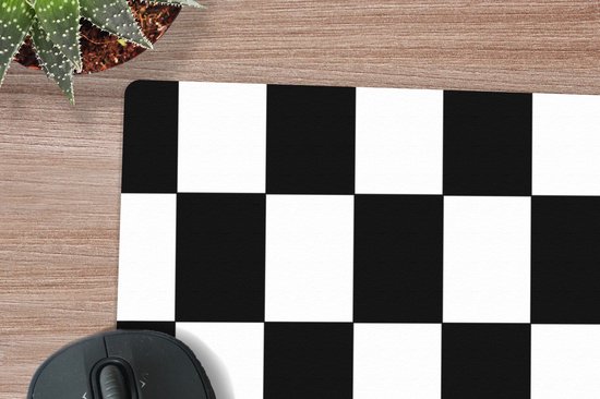 Detail van een XL muismat met een zwart-wit schaakbordpatroon op een houten bureau.